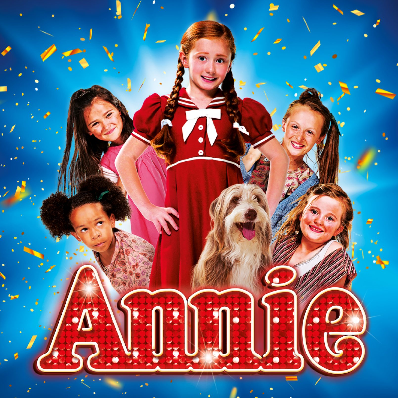 Young girl in a red dress with braided hair, surrounded by five children and a dog, smiles brightly under confetti on a blue background. Text reads "Annie."