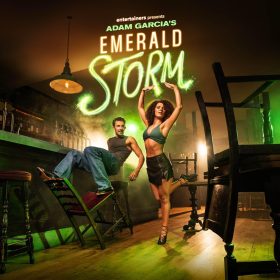 Two dancers perform energetically in a dimly lit bar with green lighting. The text "Adam Garcia's Emerald Storm" glows above them, creating a lively atmosphere.