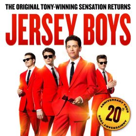 Four men in bright red suits, two wearing sunglasses, stand confidently against a white background. Bold red text reads "Jersey Boys" above them.