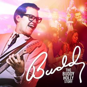 A vibrant image featuring a smiling musician in glasses and a suit playing guitar, surrounded by a colourful, energetic stage scene. Text reads “Buddy: The Buddy Holly Story.”