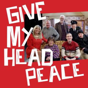 A cheerful group photo with seven people sitting and standing around a sofa in a retro-style room. Bold white text reads "Give My Head Peace" on a red background.