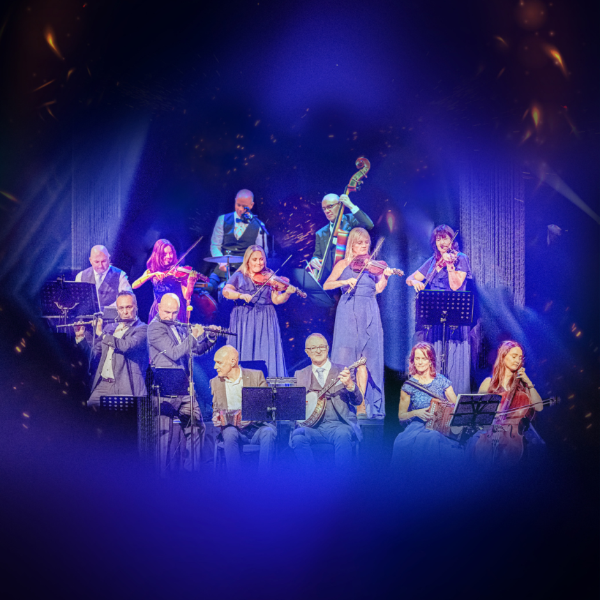 The Kilfenora Ceílí Band performs on stage - musicians in elegant attire play violins, flutes, and a cello, surrounded by a blue and purple glow.