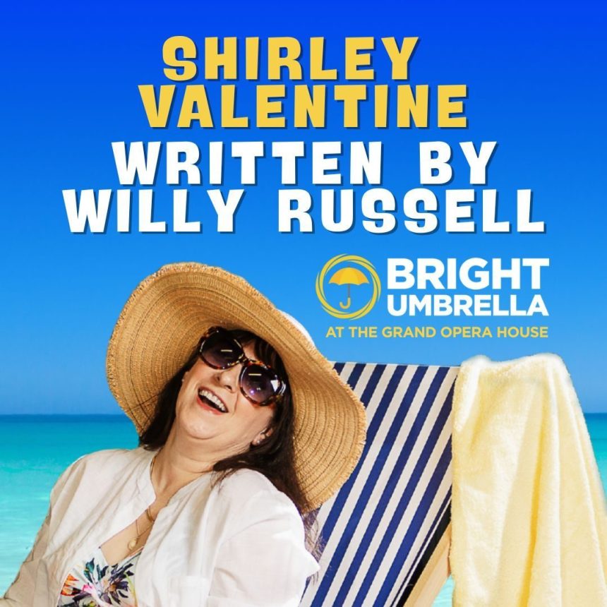 A woman in a sunhat and sunglasses smiles joyfully on a beach chair. Text reads "Shirley Valentine" by Willy Russell. "Bright Umbrella at the Grand Opera House." Blue sky and sea background convey a cheerful vibe.